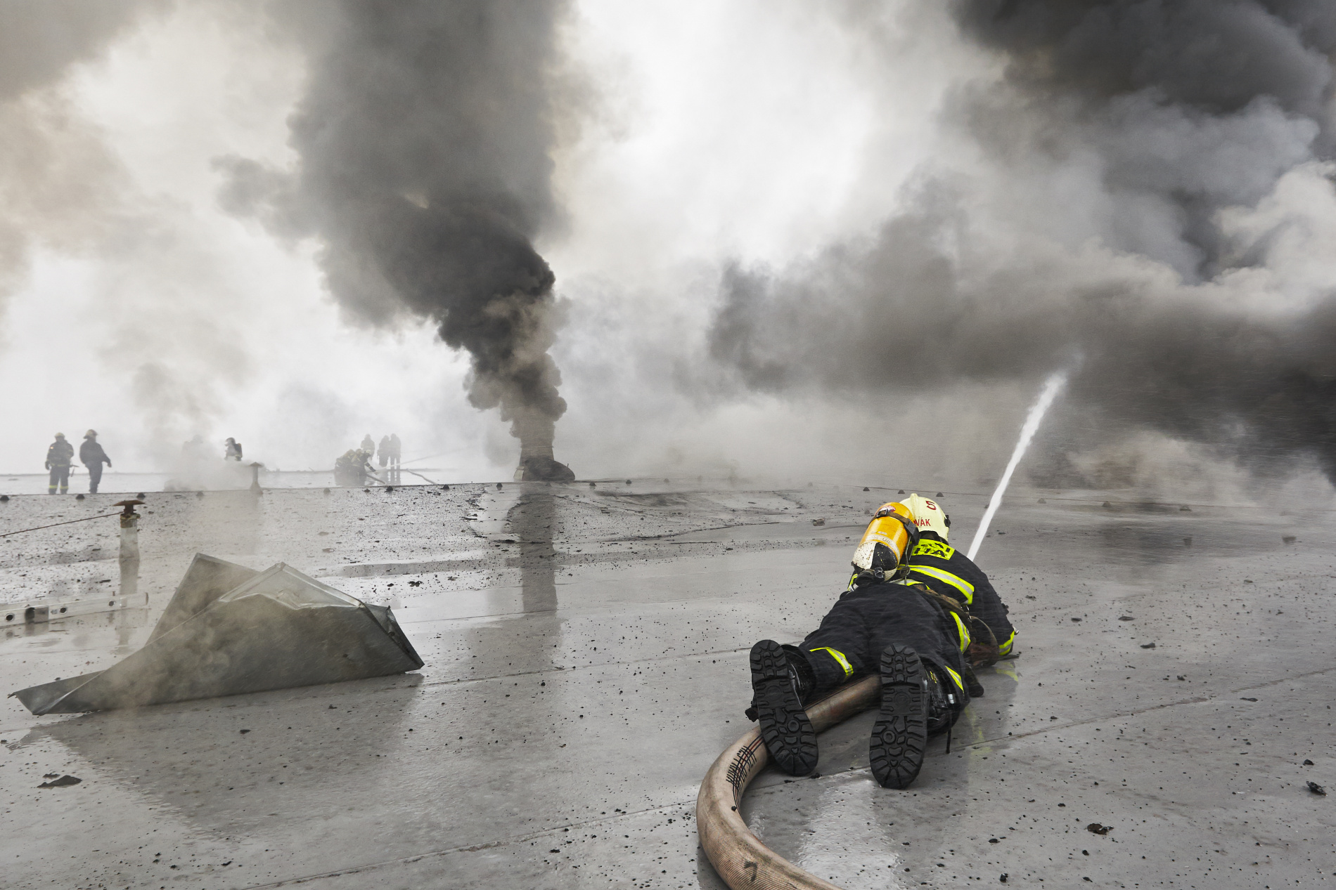  Po řadě ústupů se však blíží chvíle, kdy se situace otočí. Všichni hasiči na střeše hořícího velkoskladu v pražské Libuši tomu věří. - (Foto: Jaromír Chalabala)